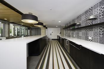 A long corridor with white countertops and black and white patterned wallpaper
